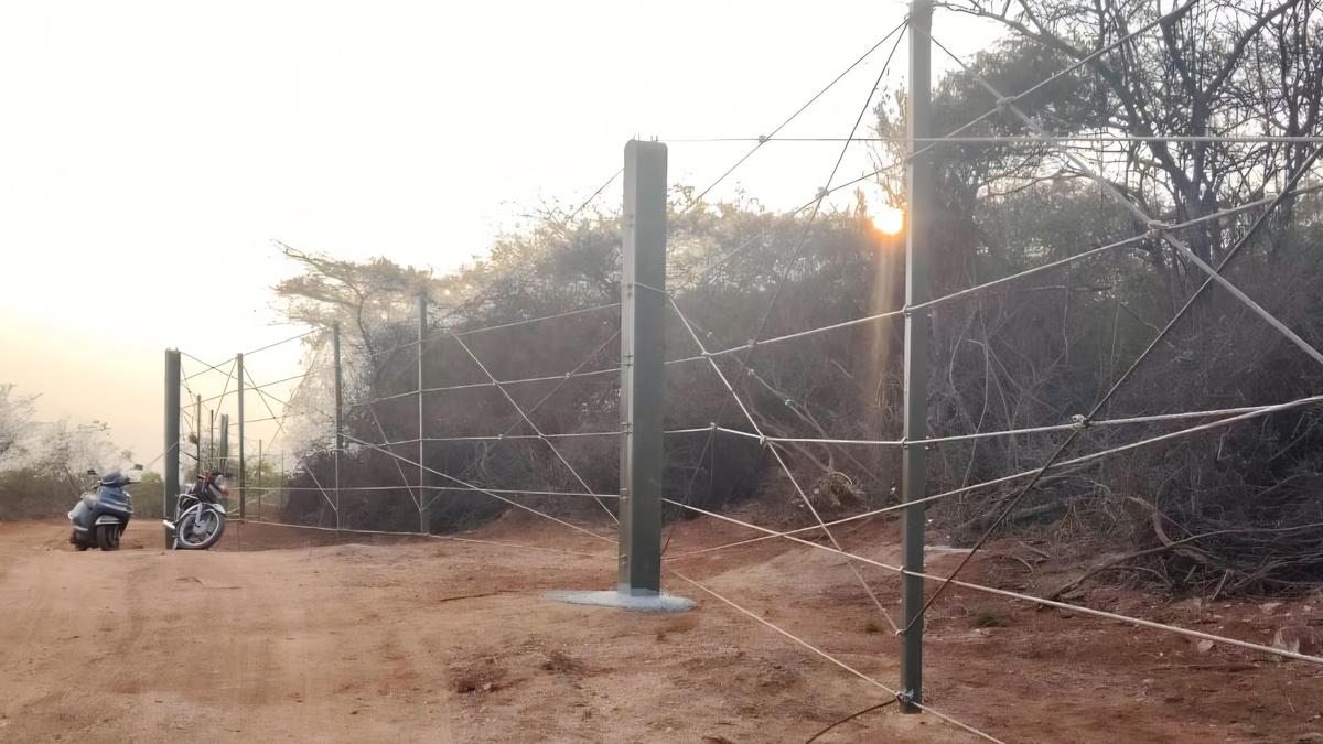 Steel wire fence installation progressing along forest boundaries in Coimbatore
